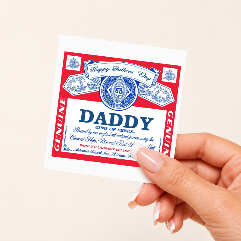 Hand holding a 'Daddy' beer label with red and blue design on a beige background