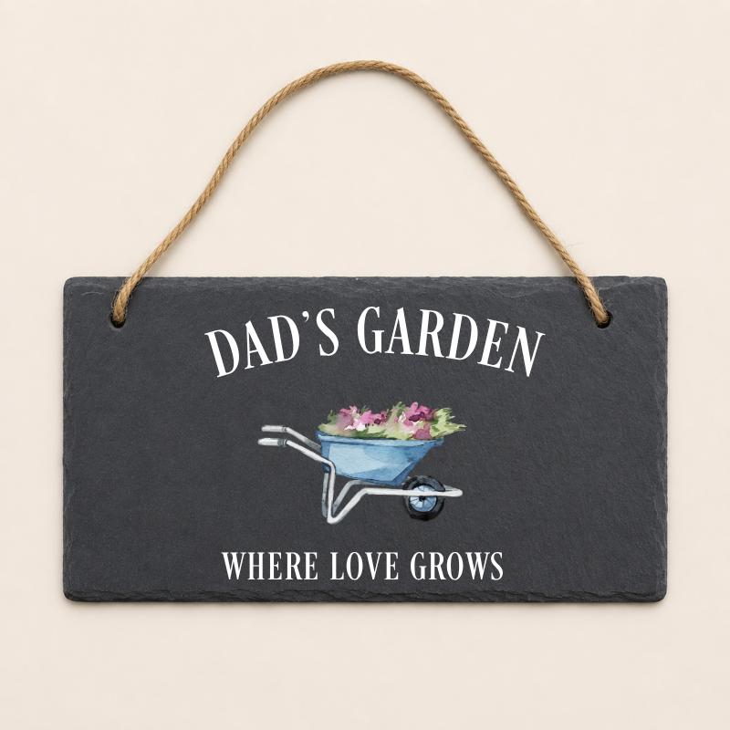 Slate sign with 'Dad's Garden' and 'Where Love Grows' text, featuring a wheelbarrow illustration on a beige background.
