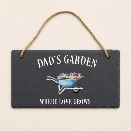 Slate sign with 'Dad's Garden' and 'Where Love Grows' text, featuring a wheelbarrow illustration on a beige background.
